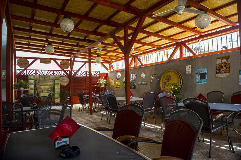 Zahrádka restaurace se stoly a zelenou konstrukcí